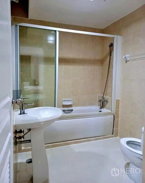 Condominium for rent in Khlong Toei, Bangkok - Bathroom with bathtub and shower screen, pedestal sink and toilet.