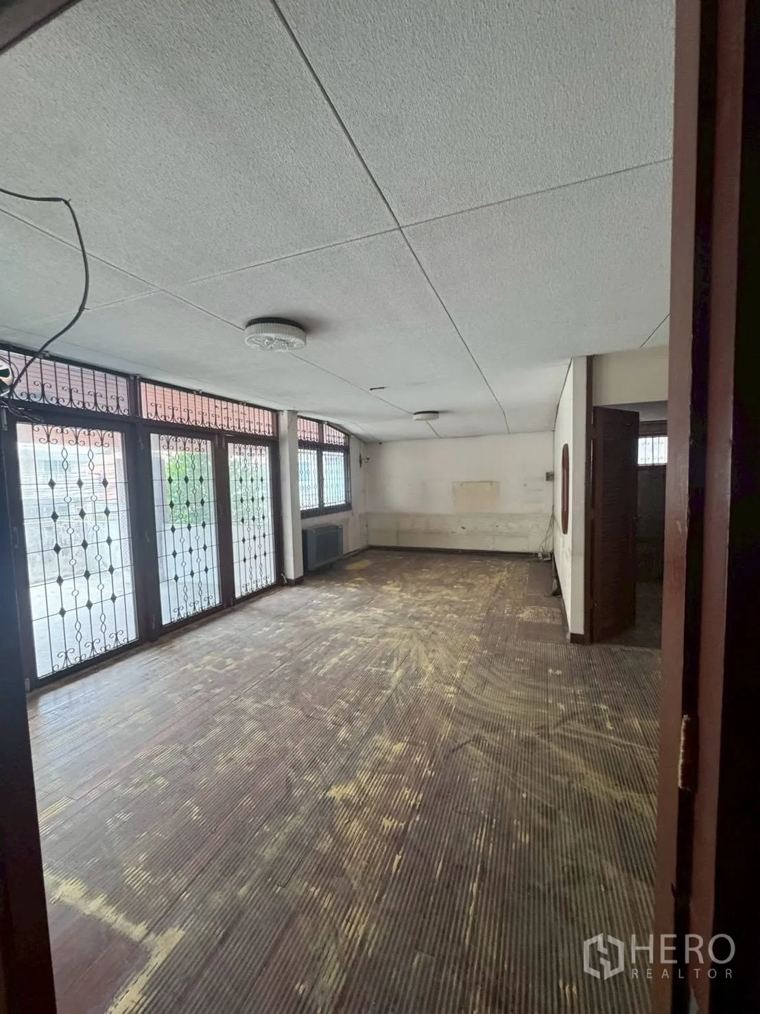 独栋房屋 for rent or sale in Watthana, Bangkok - 室内大房间，木地板与带铁艺的落地玻璃门窗。