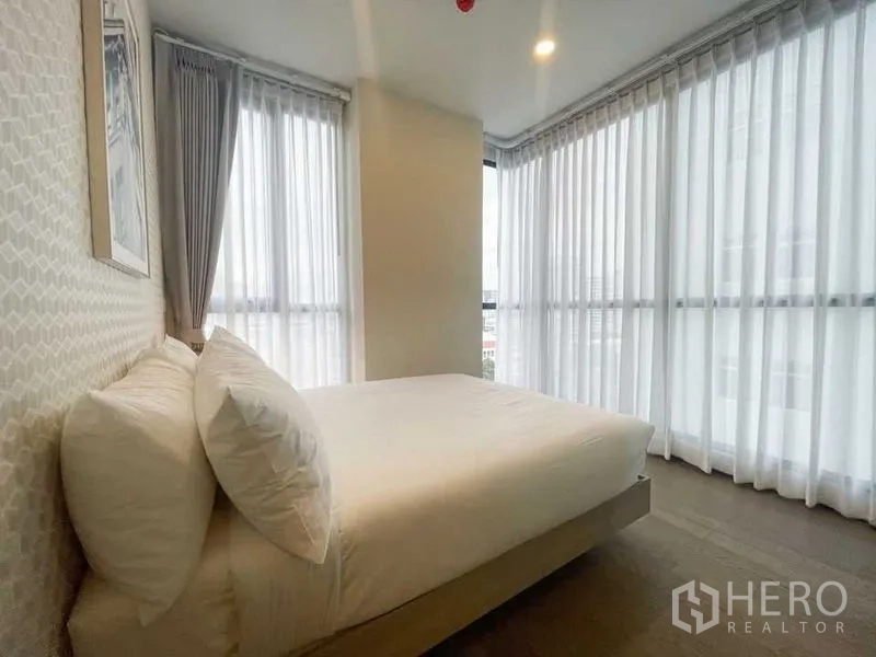 公寓 出租在Ratchathewi, Bangkok - 转角卧室，三面落地窗与白色窗帘，引入大量自然光。