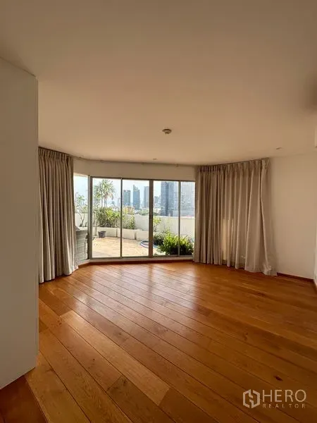 Condominium for rent in Khlong Toei, Bangkok - Bright living room with sliding glass doors opening to a large terrace and skyline views.