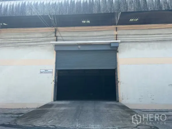 Warehouse for rent in Mueang Samut Prakan, Samut Prakan - Warehouse entrance featuring a wide roller shutter door and truck-friendly loading ramp.