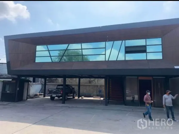 Warehouse for rent in Samut Prakan - Modern glass-façade office building with covered parking at the warehouse entrance.