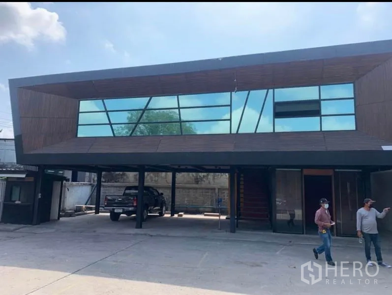 Warehouse for rent in Samut Prakan - Modern glass-façade office building with covered parking at the warehouse entrance.