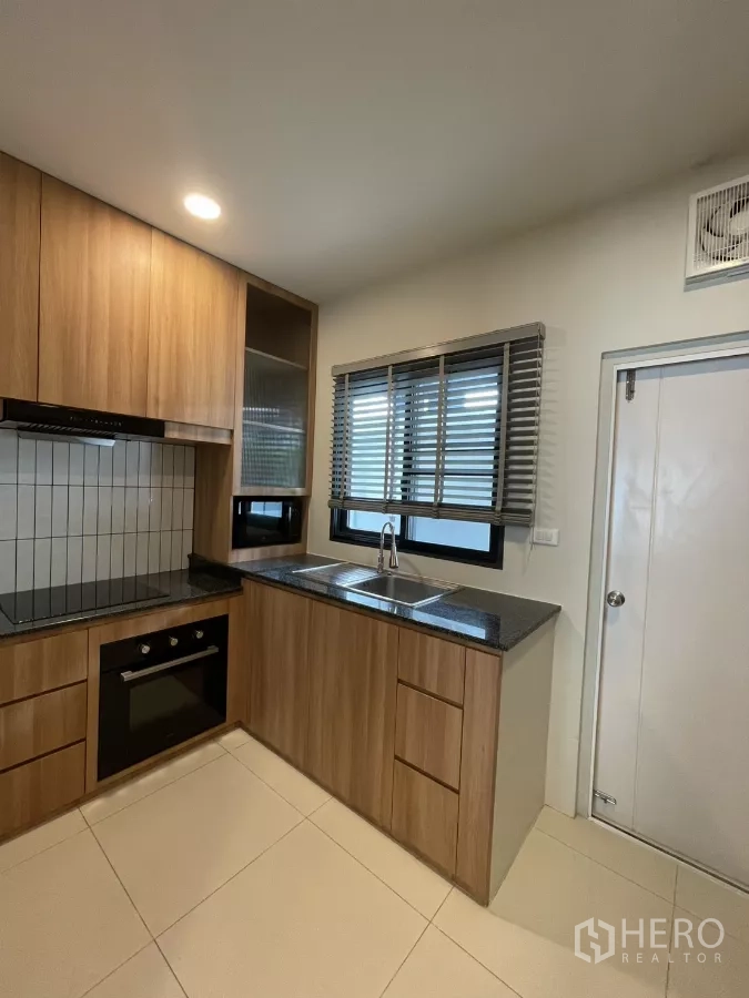 独立式住宅 出租在Bang Phli, Samut Prakan - 厨房角度展示窗下水槽、橱柜与嵌入式烤箱。