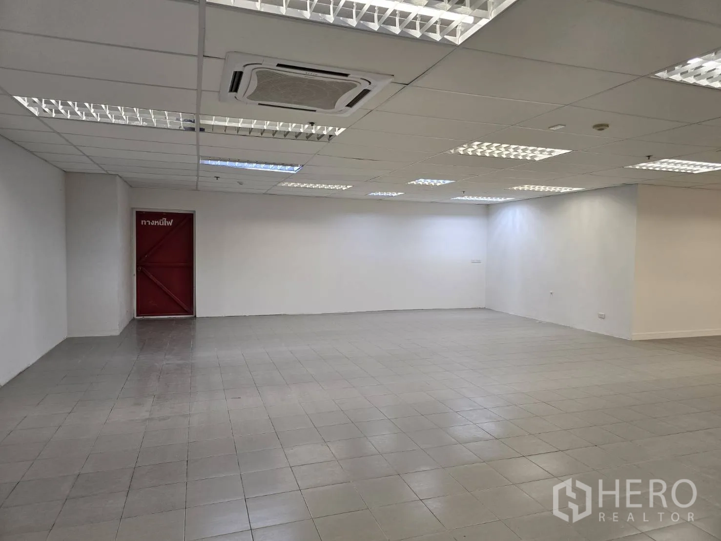 พื้นที่ขายของ for rent in Watthana, Bangkok - พื้นที่ค้าปลีกปูกระเบื้องสีเทา ผนังสีขาว และประตูทางหนีไฟสีแดง