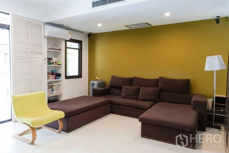 Townhouse for sale - Living room with brown sectional sofa, green accent wall and recessed lights.