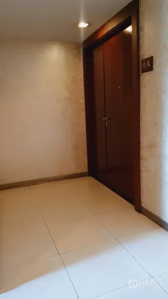 公寓 出租在Khlong Toei, Bangkok - 公寓走廊与木质入户门，瓷砖地面与壁灯。