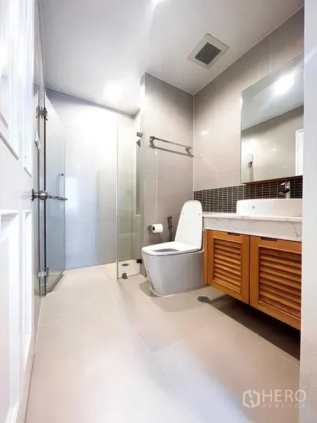 Condominium for rent - Modern bathroom featuring a glass shower, tiled walls and a vanity with louvered cabinets.
