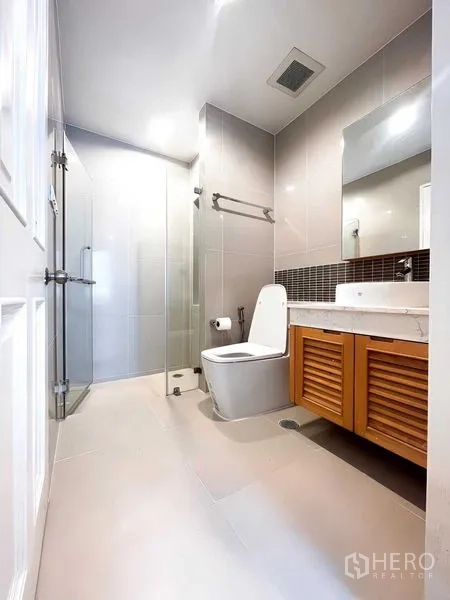 Condominium for rent - Modern bathroom featuring a glass shower, tiled walls and a vanity with louvered cabinets.