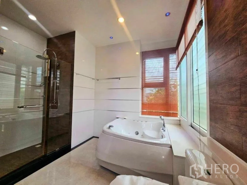 Detached House for rent in Chatuchak, Bangkok - Spa-style bathroom featuring a jacuzzi tub beside tall windows and a glass walk-in shower.