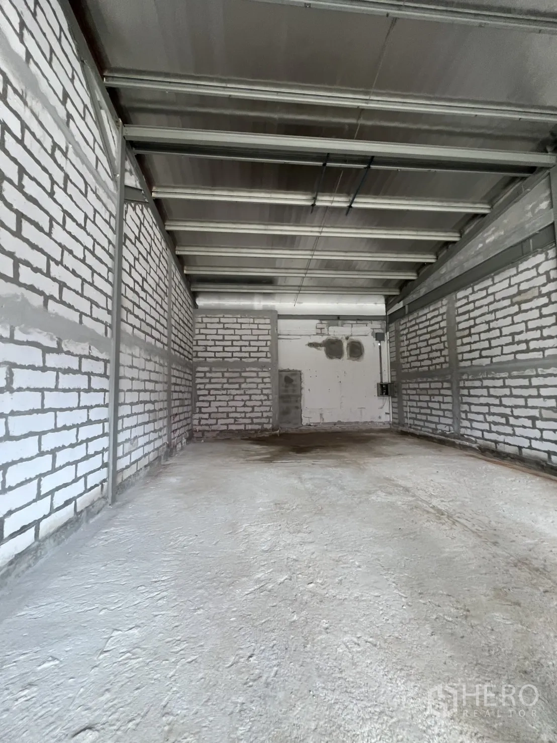 Retail Space for rent - Deep interior shell space with exposed steel beams, white brick walls and concrete floor