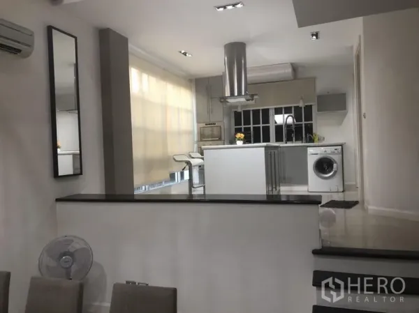 Townhouse for rent in Bang Kapi, Bangkok - Split-level view to the open-plan kitchen with island, range hood and large windows.