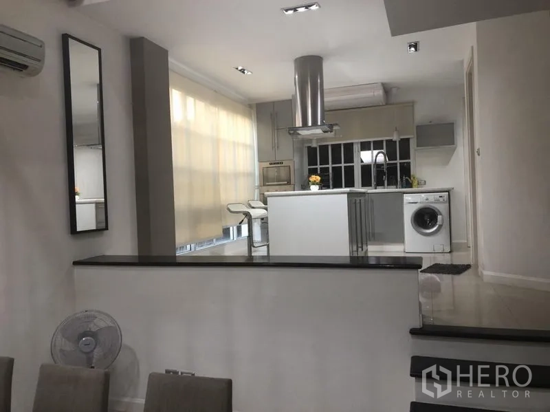 Townhouse for rent in Bang Kapi, Bangkok - Split-level view to the open-plan kitchen with island, range hood and large windows.