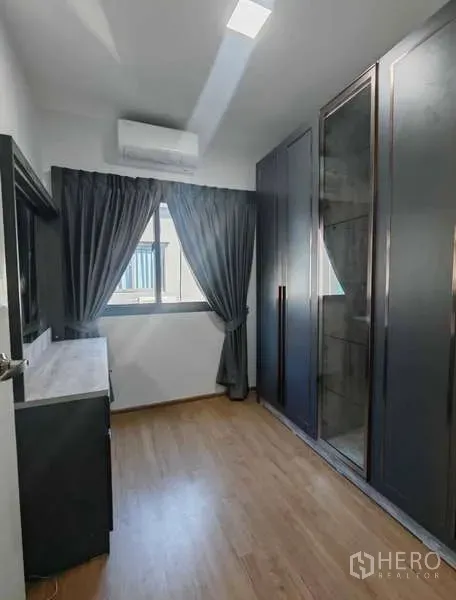 Townhouse for rent in Bang Phli, Samut Prakan - Compact bedroom with wood floor, window with dark curtains, built-in glass wardrobe and air conditioner.