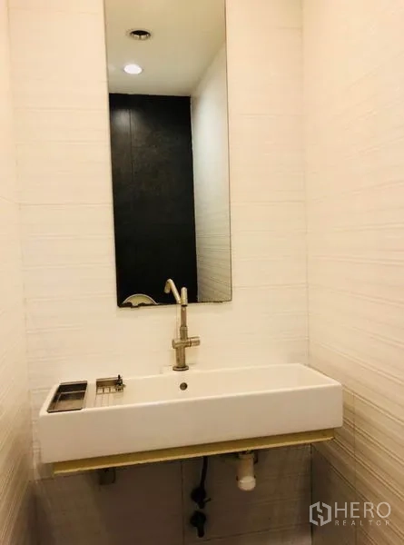 Home Office for rent in Huai Khwang, Bangkok - Compact bathroom with large wall mirror and rectangular basin.