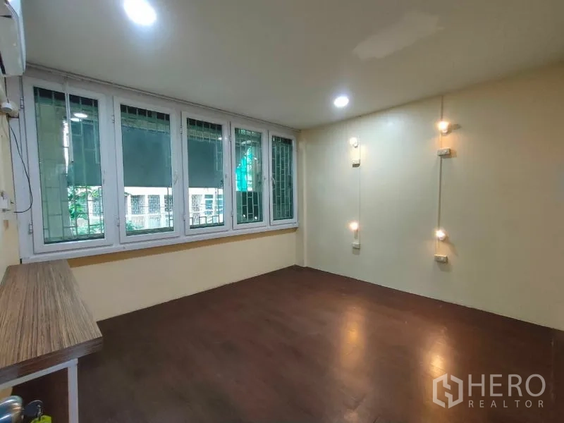 店屋 出租或出售在Bang Rak, Bangkok - 房间铺深色木地板，宽窗配护栏，墙面点缀小射灯。