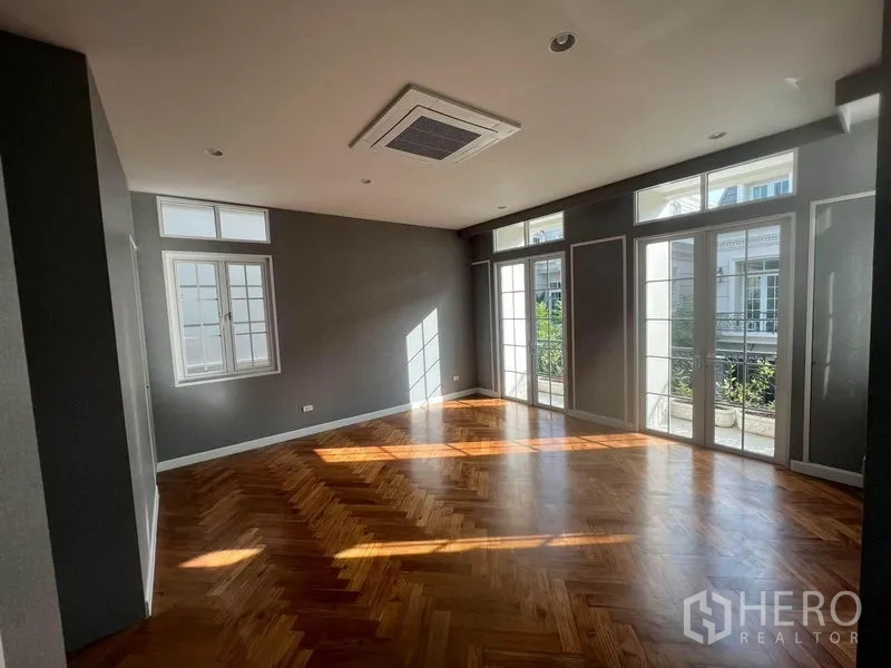 Detached House for sale in Yan Nawa, Bangkok - Spacious bedroom with parquet floor and multiple French doors to a balcony.