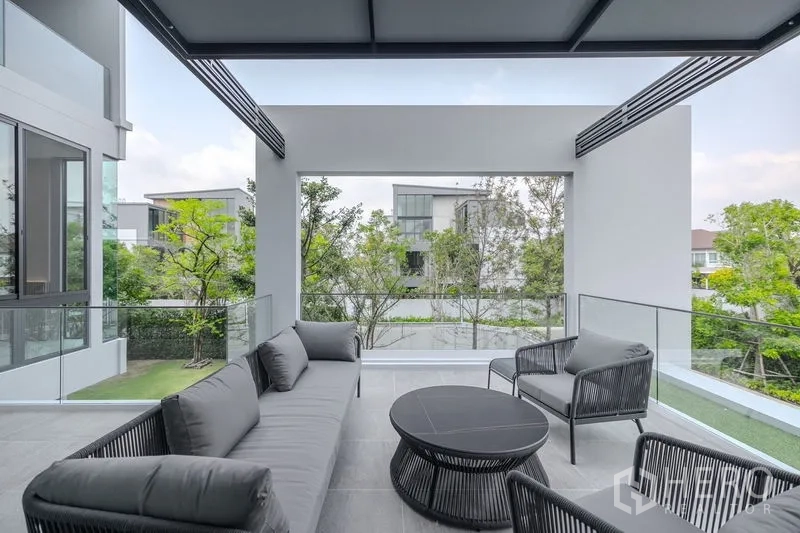 Detached House for rent in Saphan Sung, Bangkok - Covered balcony lounge with sofa set and neighborhood greenery.