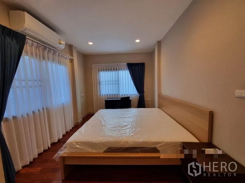 Detached House for rent in Bang Khae, Bangkok - Secondary bedroom with double bed, desk, air conditioning and wood floors.