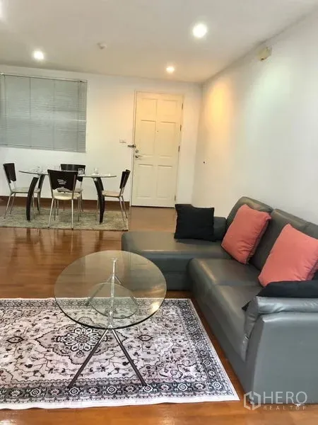公寓 出租或出售在Watthana, Bangkok - 舒适起居区，面向入户门与餐桌，木地板和筒灯照明