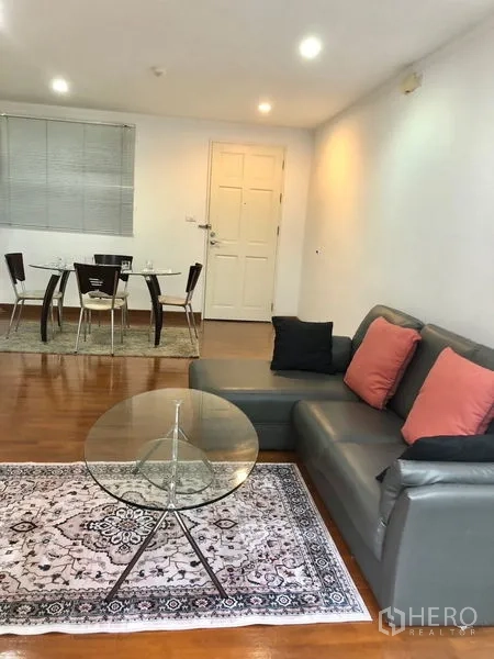 公寓 出租或出售在Watthana, Bangkok - 舒适起居区，面向入户门与餐桌，木地板和筒灯照明