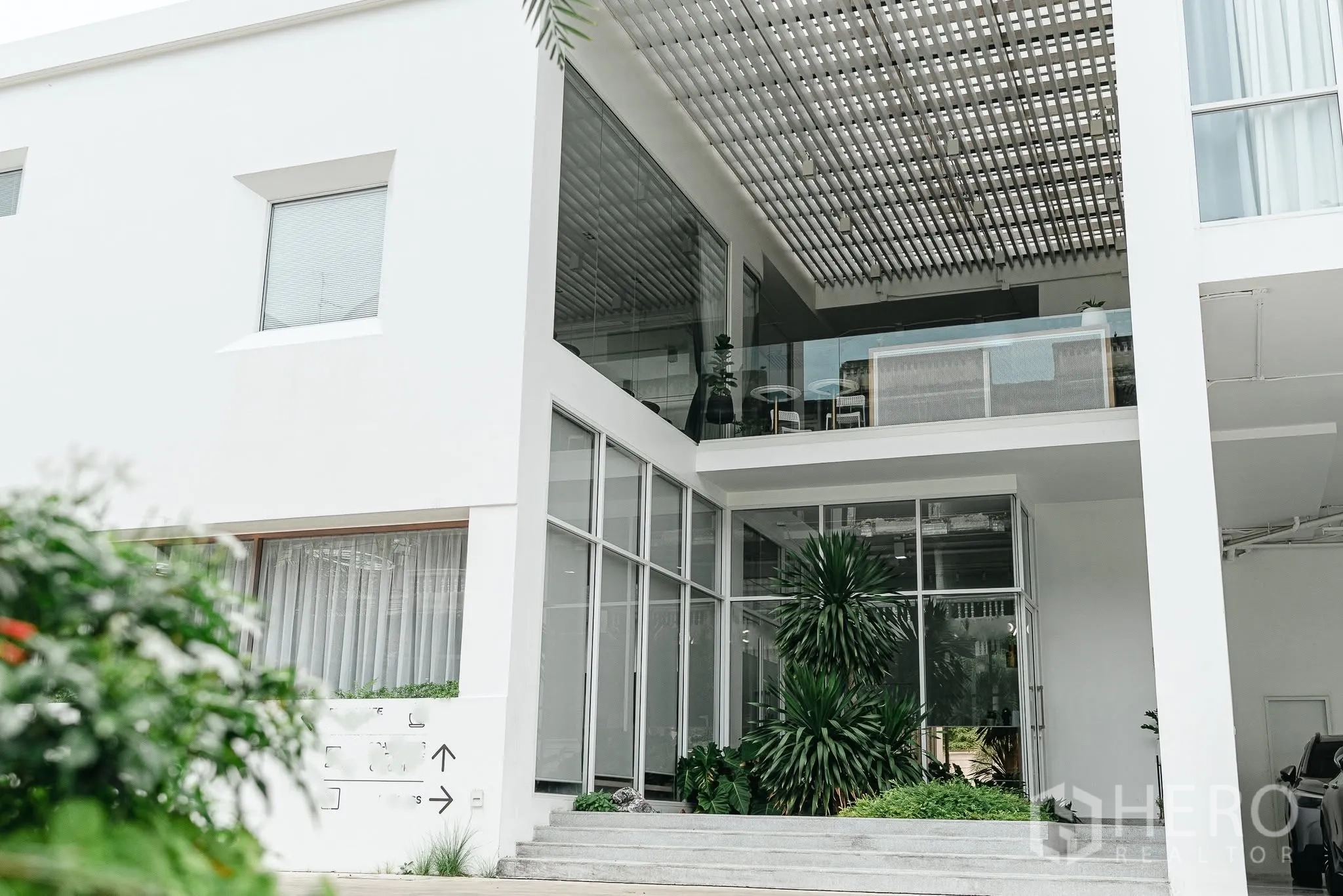 Office Space for rent in Bang Kapi, Bangkok - Contemporary entrance with glass walls, shaded terrace, steps, and lush plants.