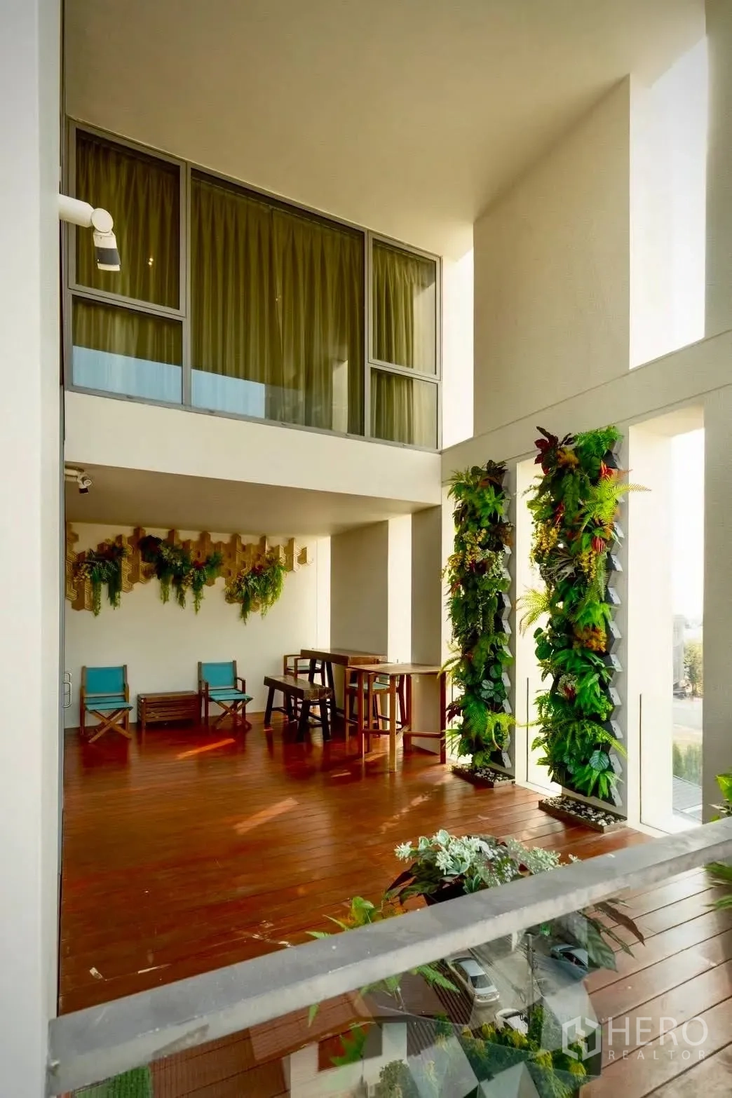 公寓 for sale in Sathon, Bangkok - 木质露台配高挑采光与垂直绿植墙，设有座椅与小桌。