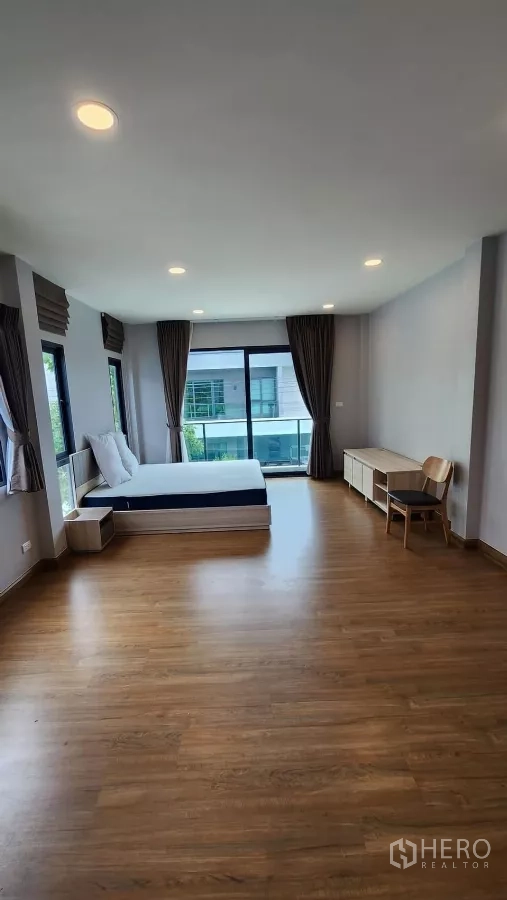 Detached House for rent in Bang Phli, Samut Prakan - Spacious master bedroom with wood flooring, bed and balcony access through sliding glass doors.