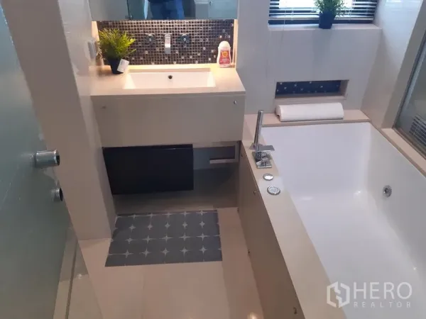 Condominium for rent in Khlong Toei, Bangkok - Bathroom featuring a deep soaking tub, vanity with mosaic backsplash, and a window.