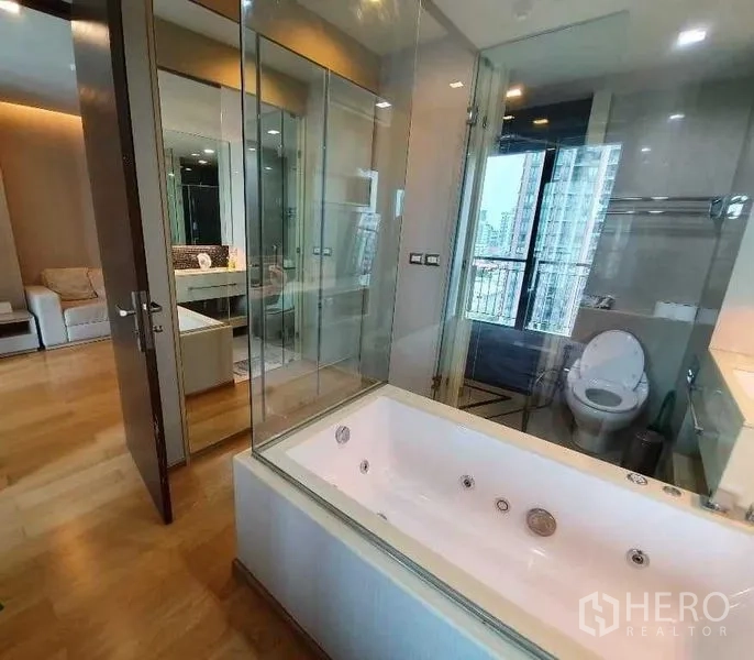 公寓 出售在Ratchathewi, Bangkok - 浴室套间设大浴缸与玻璃墙，淋浴与马桶分区，可见城市景观。
