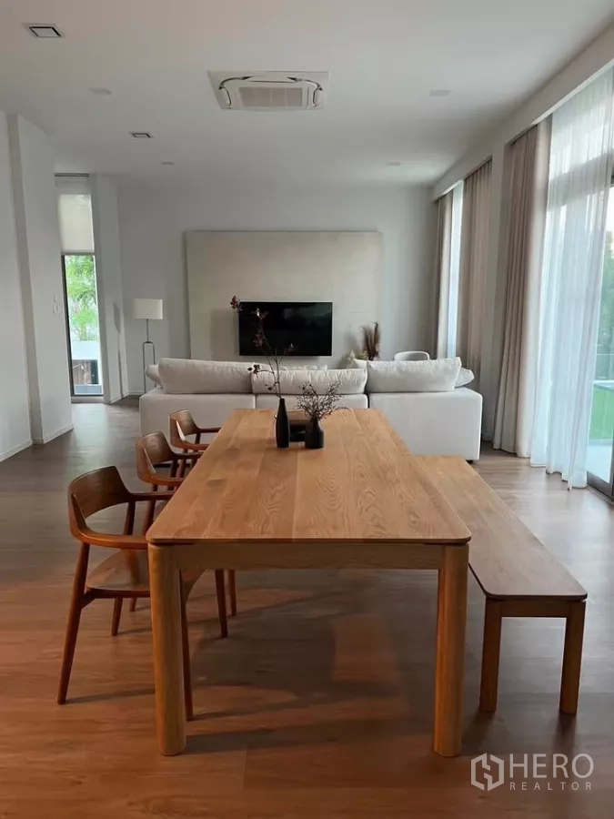 Detached House for rent in Saphan Sung, Bangkok - Open-plan dining and living area with a wooden dining table, bench seating and wall-mounted TV.