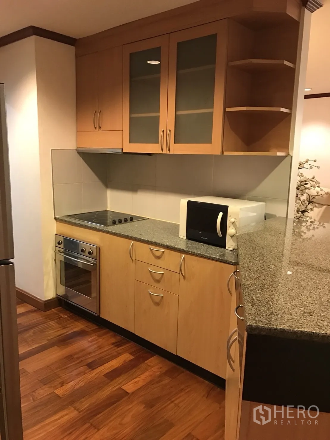 Condominium for rent in Khlong Toei, Bangkok - Compact U-shaped kitchen with granite countertop, oven, cooktop and microwave.