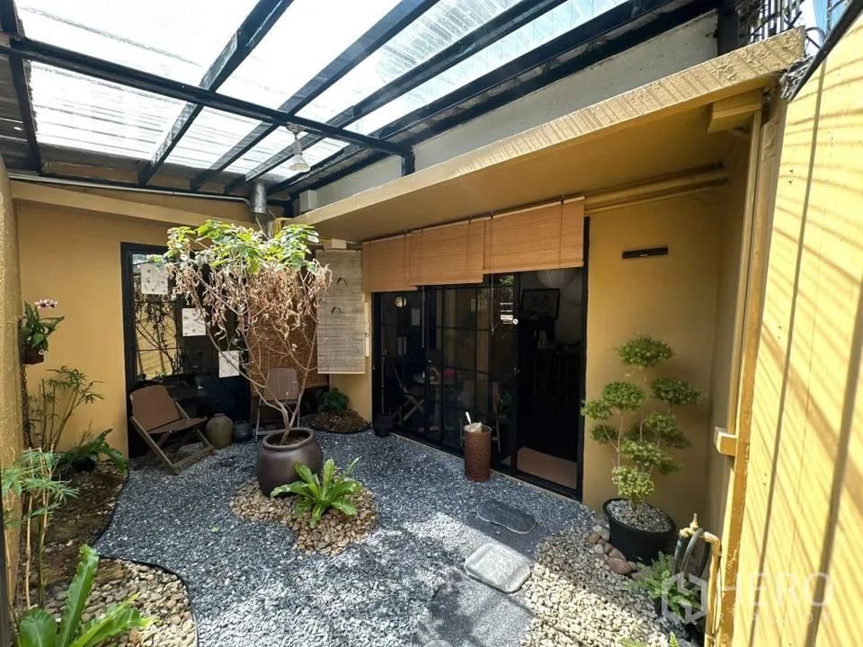 Retail Space for rent in Khlong Toei, Bangkok - Covered courtyard with pebbled ground, potted plants, and black-framed sliding doors.
