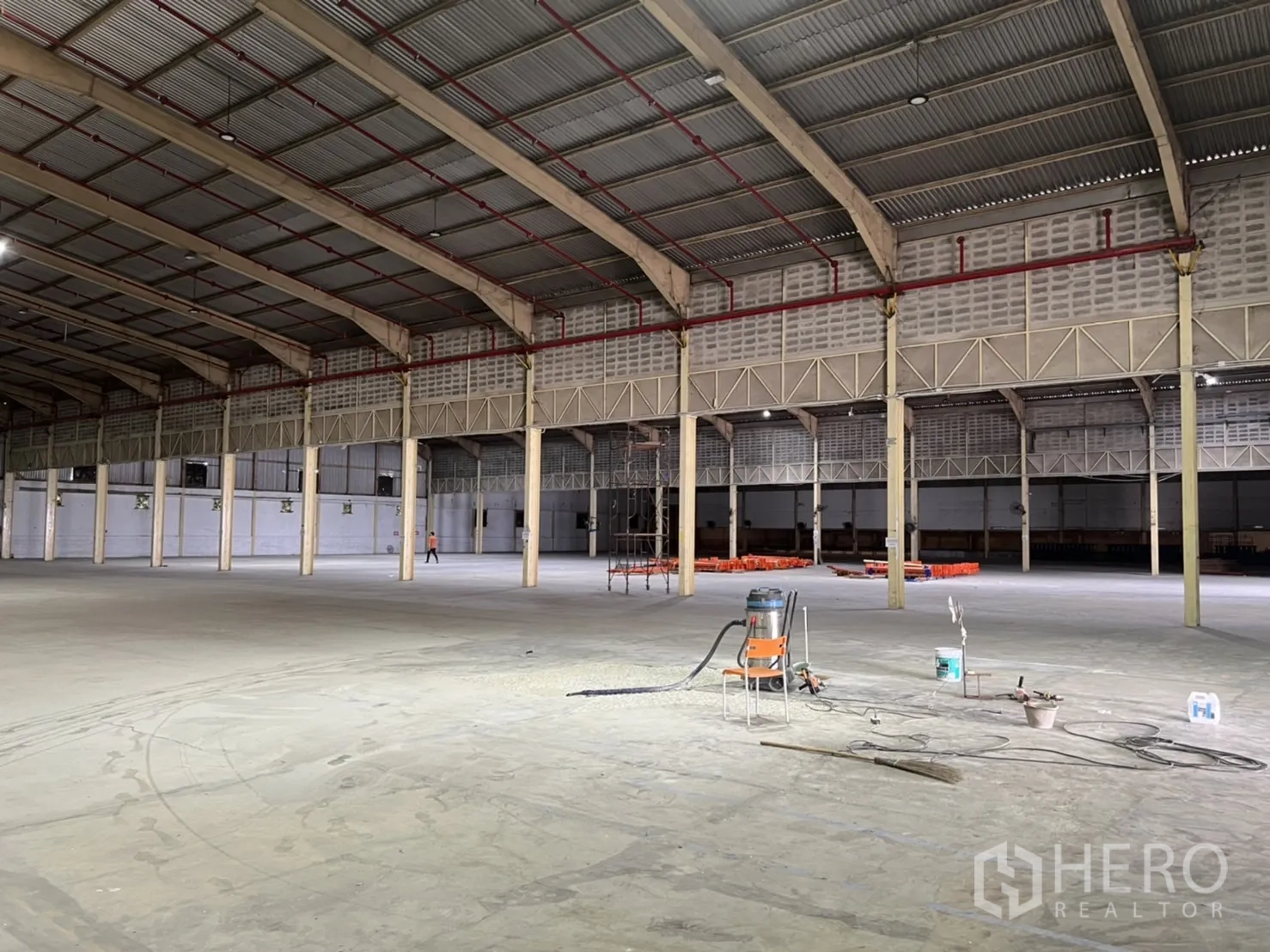 Warehouse for rent in Mueang Samut Prakan, Samut Prakan - Interior view with a column grid beneath a metal roof, lighting and ventilation fans.