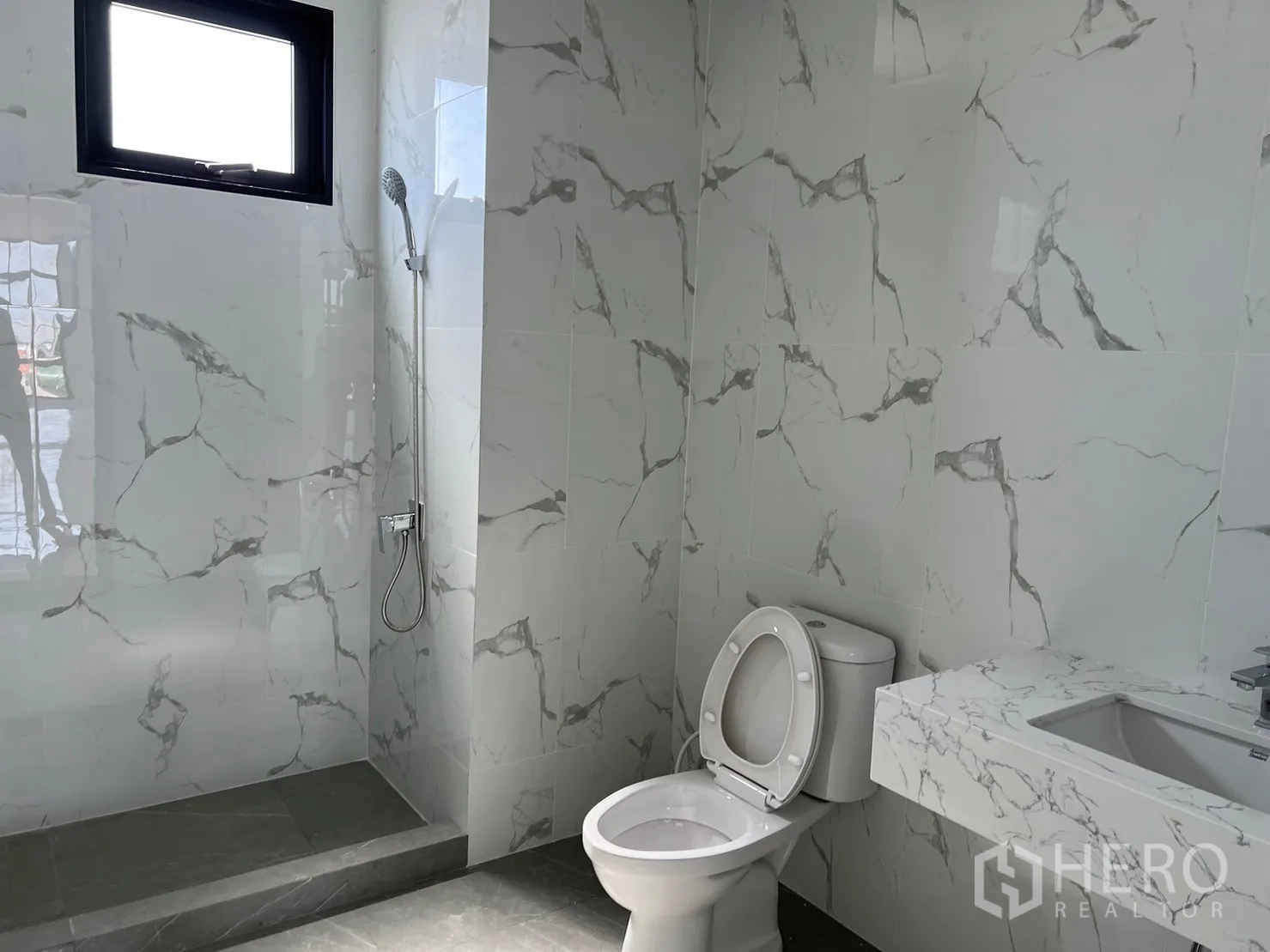 Warehouse for rent in Samut Prakan - Bathroom with shower area, toilet and marble-look vanity.