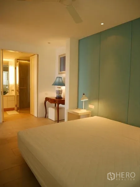 Condominium for rent in Khlong Toei, Bangkok - Bedroom with teal accent wall, bedside lamps and a ceiling fan.