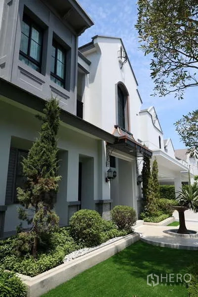 Detached House for rent or sale in Saphan Sung, Bangkok - Landscaped garden and European-style house facade with gable roofs.
