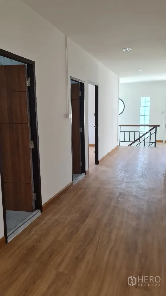 Detached House for rent in Lat Phrao, Bangkok - Upper hallway with wood flooring and several bedroom doors.