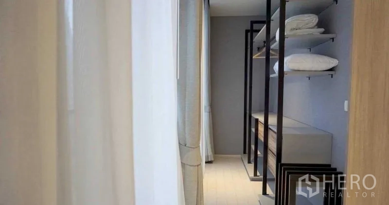 Condominium for rent in Pathum Wan, Bangkok - Walk-in closet corridor with open shelving, drawers and light curtains.