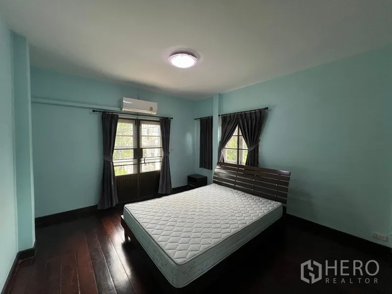 บ้าน ให้เช่าในBang Na, Bangkok - ห้องนอนหลักพร้อมผ้าม่านเข้ม ประตูระเบียง และพื้นไม้