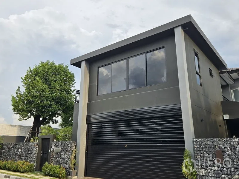 独立式住宅 出售在Thawi Watthana, Bangkok - 特写黑色卷帘车库门及二楼窗户。