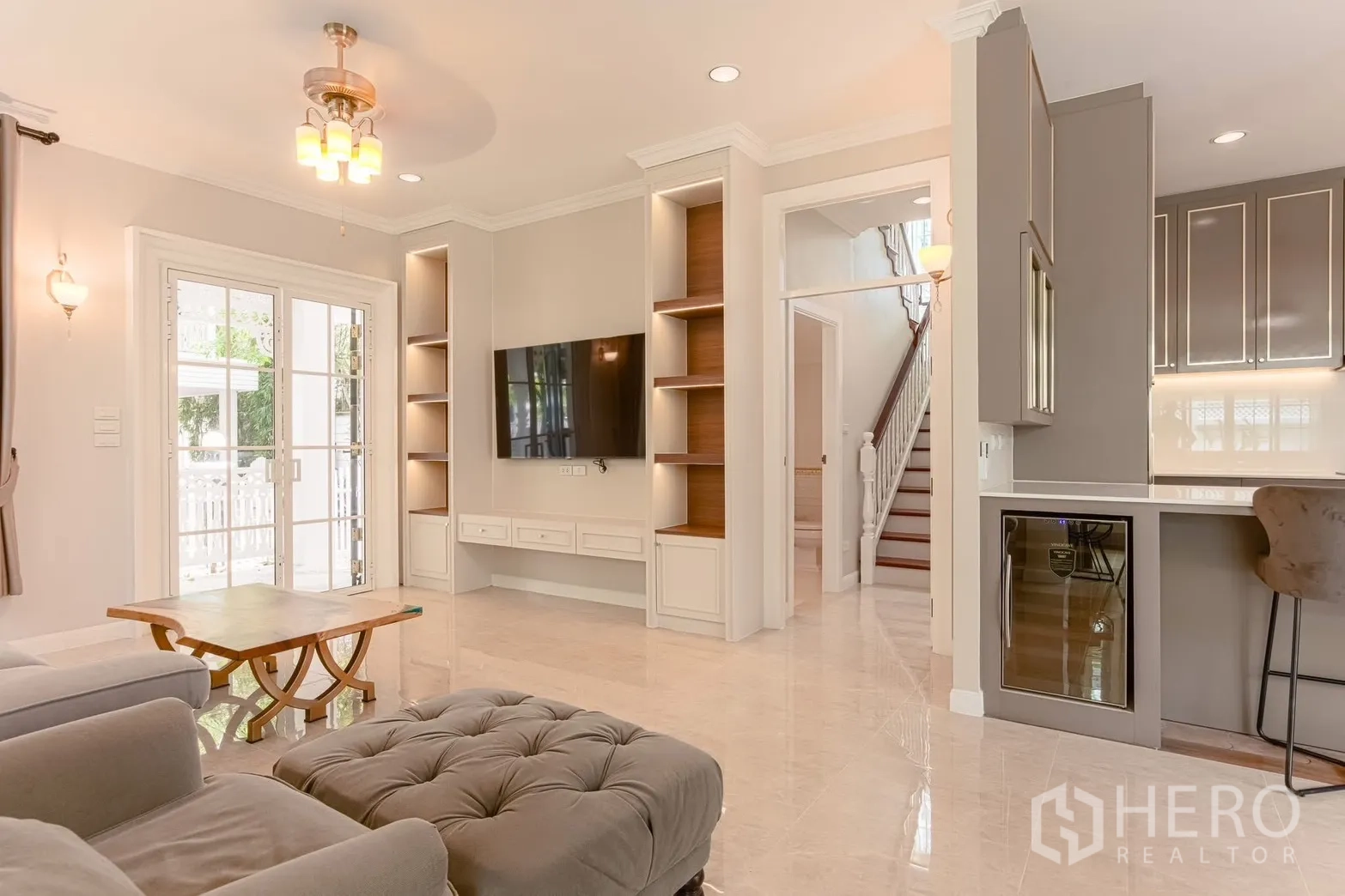 บ้านเดี่ยว for rent in Bang Na, Bangkok - ผนังทีวีห้องนั่งเล่นพร้อมชั้นบิลท์อิน บันได และตู้แช่ไวน์