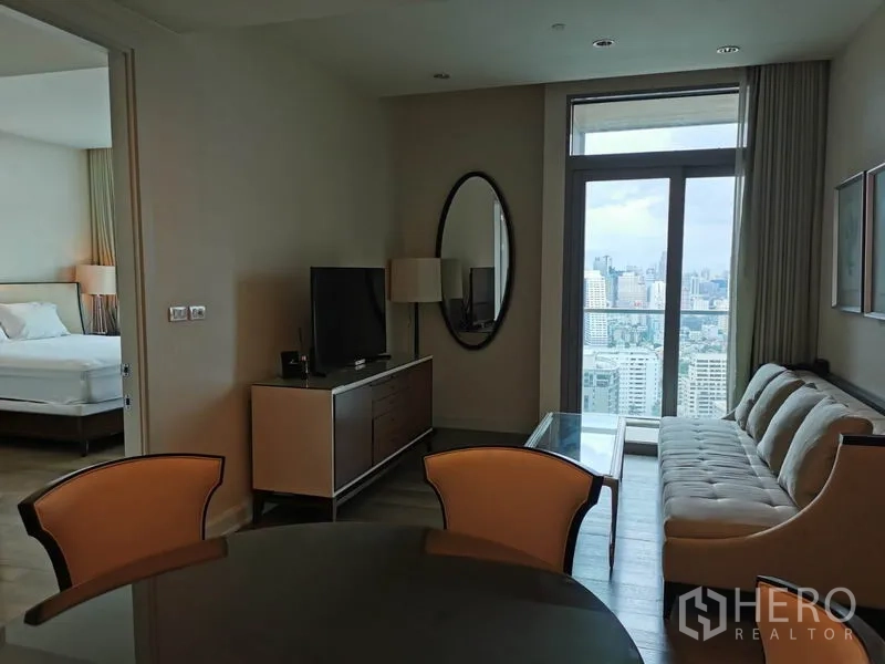 Condominium for rent in Pathum Wan, Bangkok - Living area with TV console, sofa and dining set beside the balcony.