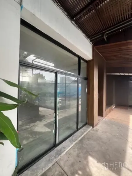Retail Space for rent - Street-facing retail frontage with large sliding glass doors and covered patio with plants.