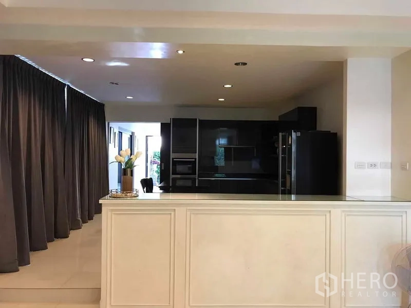 Detached House for sale in Wang Thonglang, Bangkok - Light-filled dining area with serving counter facing a sleek black kitchen
