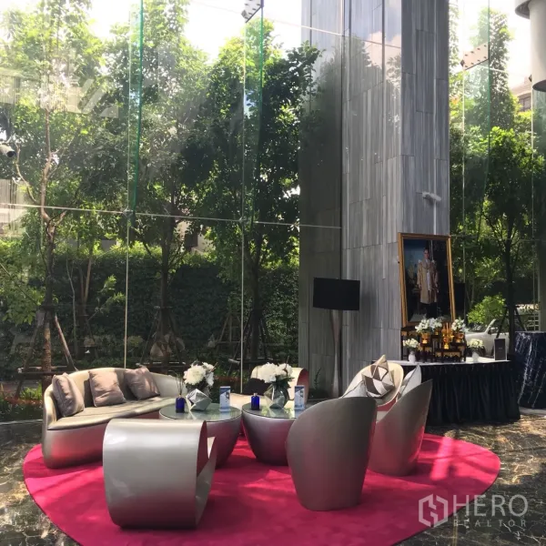 公寓 出租或出售在Watthana, Bangkok - 挑高玻璃墙大堂，现代家具与室外绿景相映。