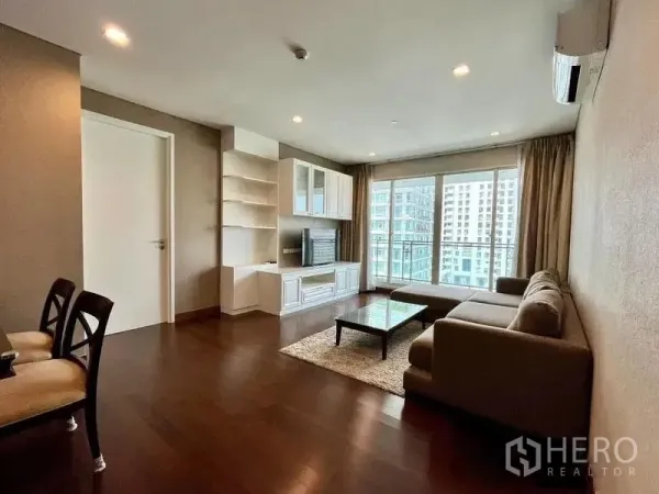 Condominium for rent in Watthana, Bangkok - Living room with sofa set, rug, and sliding doors to a balcony view.