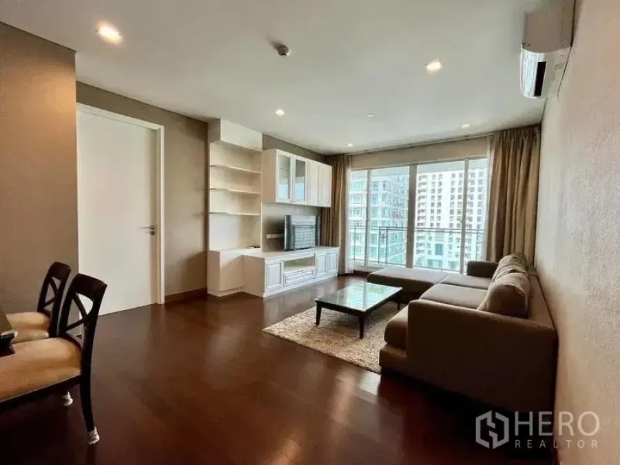 Condominium for rent in Watthana, Bangkok - Living room with sofa set, rug, and sliding doors to a balcony view.