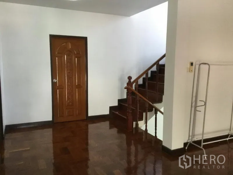 独立式住宅 出租或出售在Huai Khwang, Bangkok - 楼梯平台处设雕花木门与抛光木楼梯和扶手。