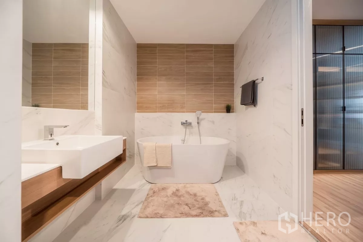 Detached House for rent in Saphan Sung, Bangkok - Modern bathroom with freestanding soaking tub, marble‑look tiles and long vanity.